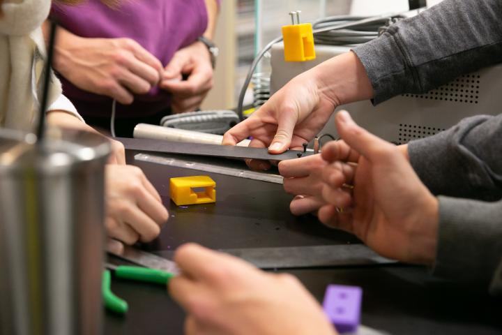 An image of a variety of student hands working with metal pieces.