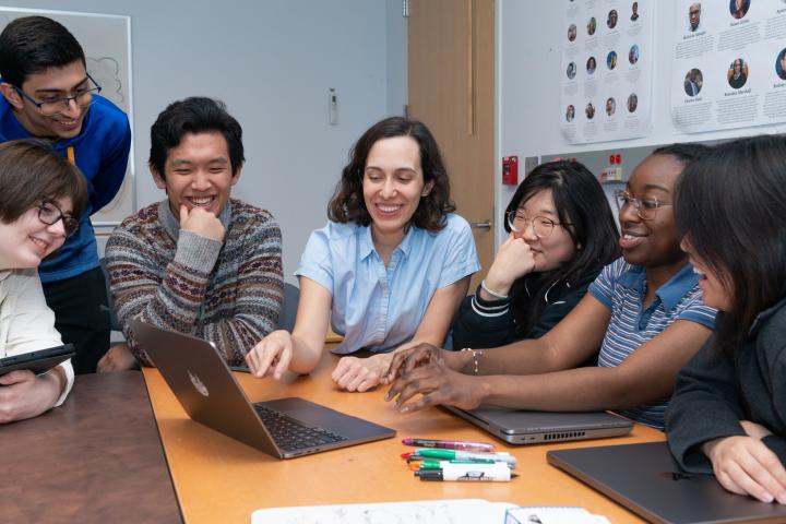 Professor Andrea Cuadra gathered around a computer with her students