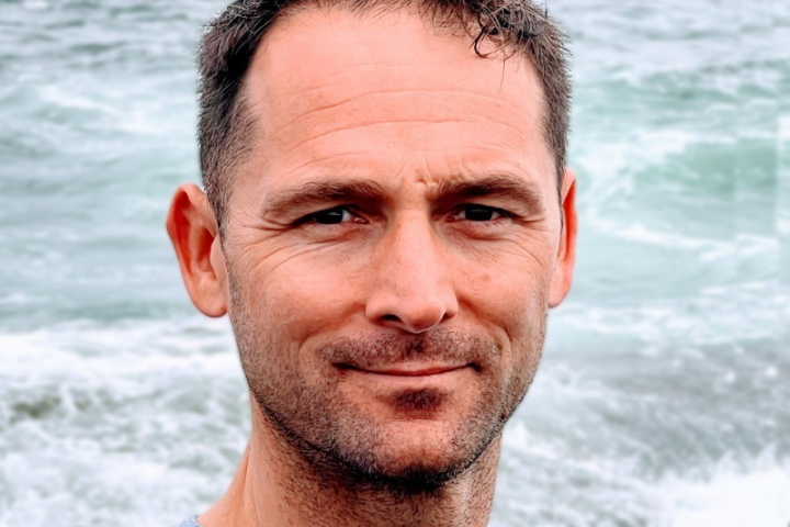 man smiling, waves as backdrop