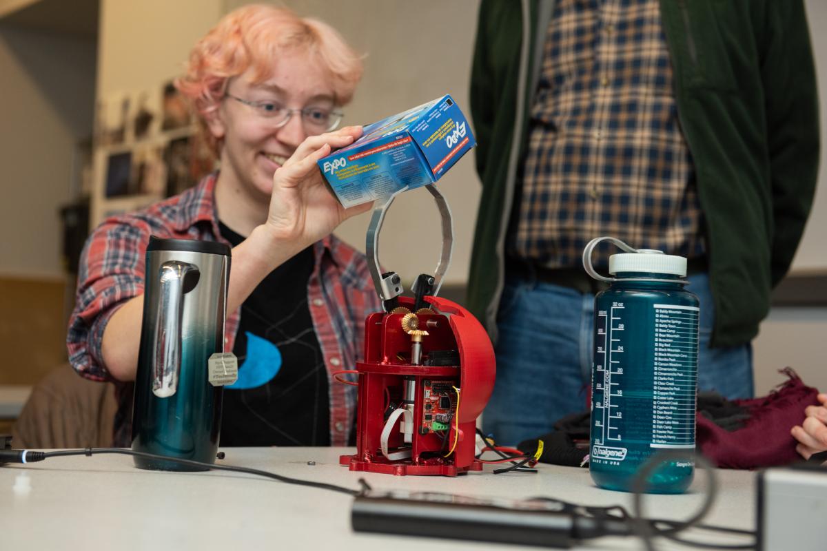A photo of an engineering student demonstrating a mechatronic system 