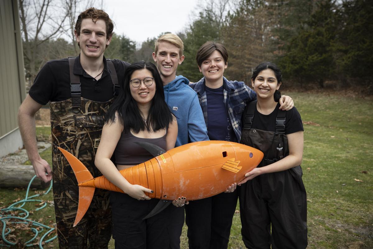 Five Olin students pose for the camera while holding an orange-colored Robot Fish.