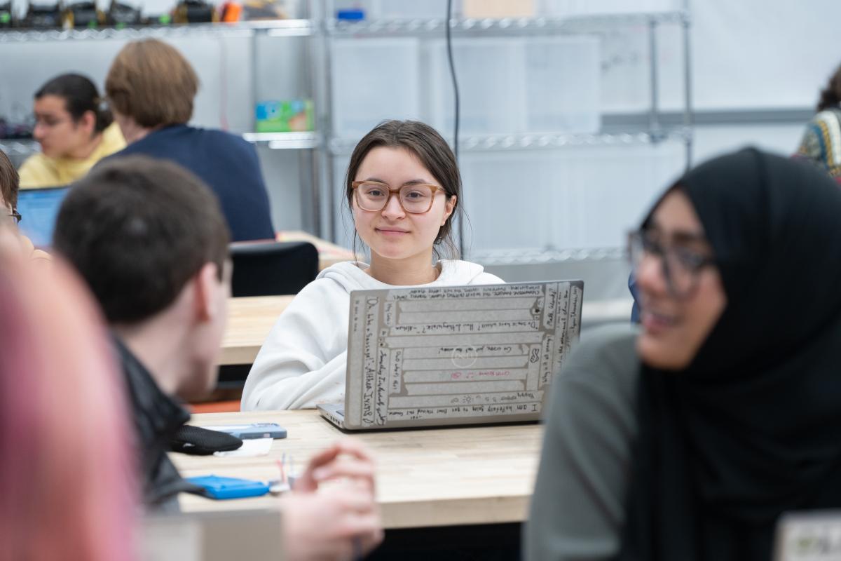 An Olin student sits at a table with laptop open during a recent QEA class.