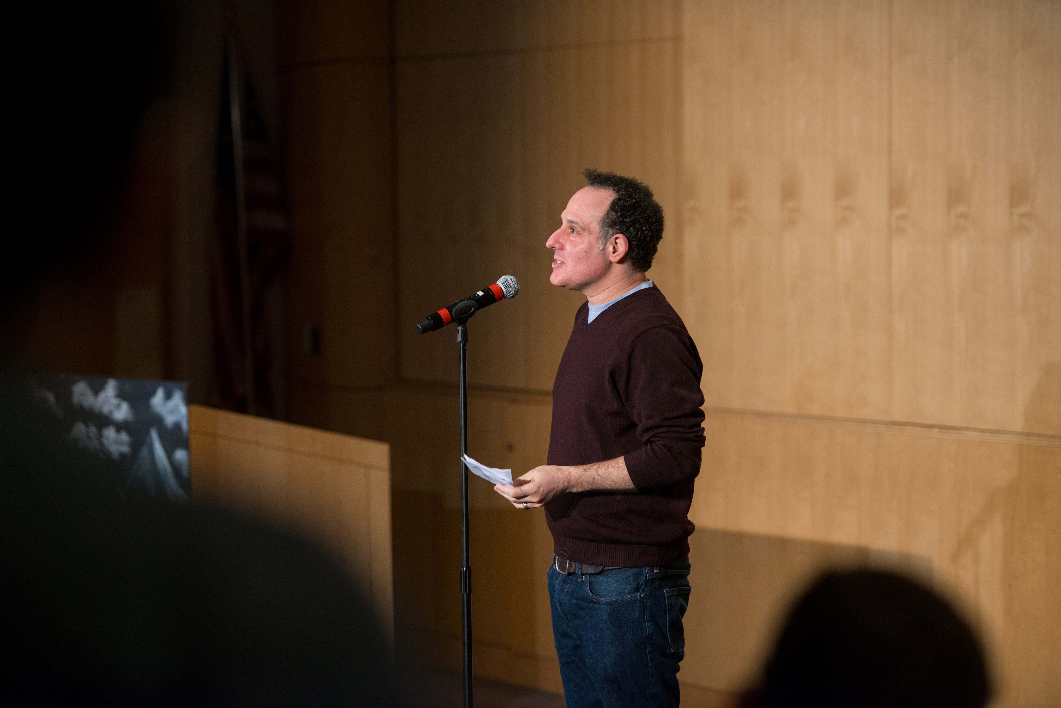 Two people standing on stage with a microphone about to tell a story