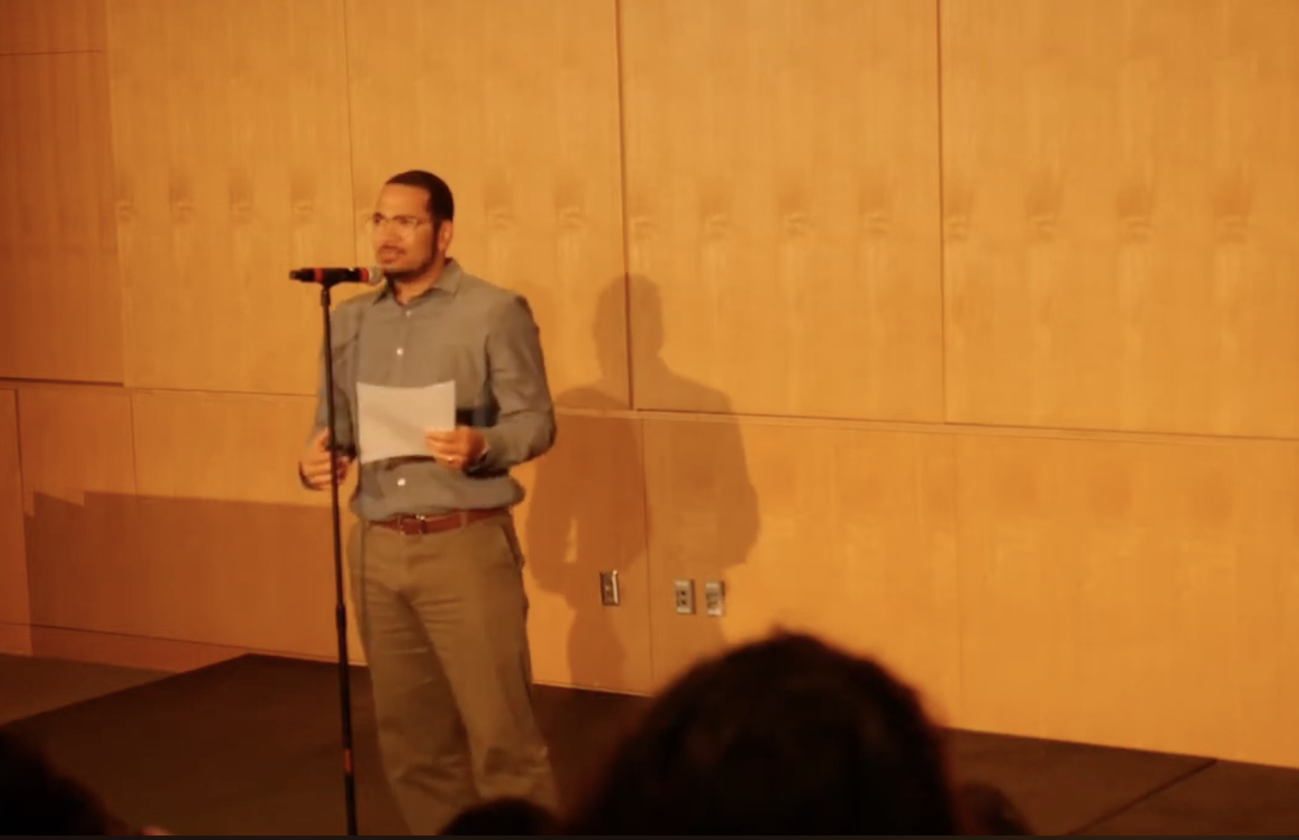 A man standing in front of a microphone holding a piece of paper