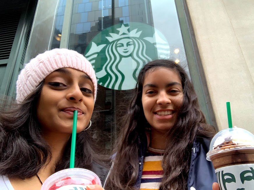 Two friends outside a Starbucks with coffee drinks.