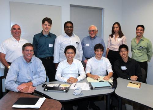 Team members sitting and standing around a desk smiling