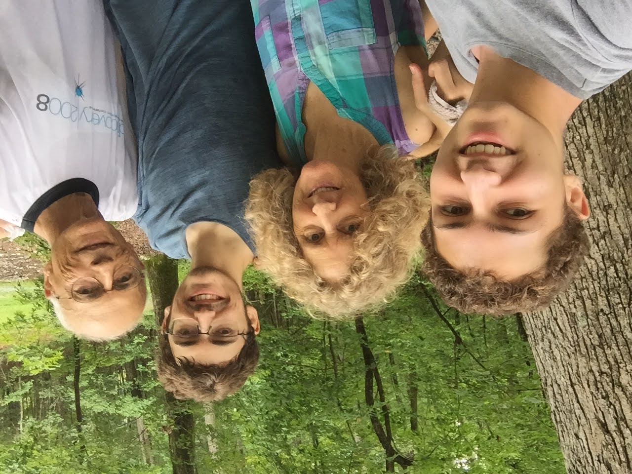 A selfie of a family of four in a wooded outdoor area.