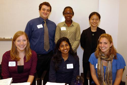 Team members sitting and standing at a desk smiling