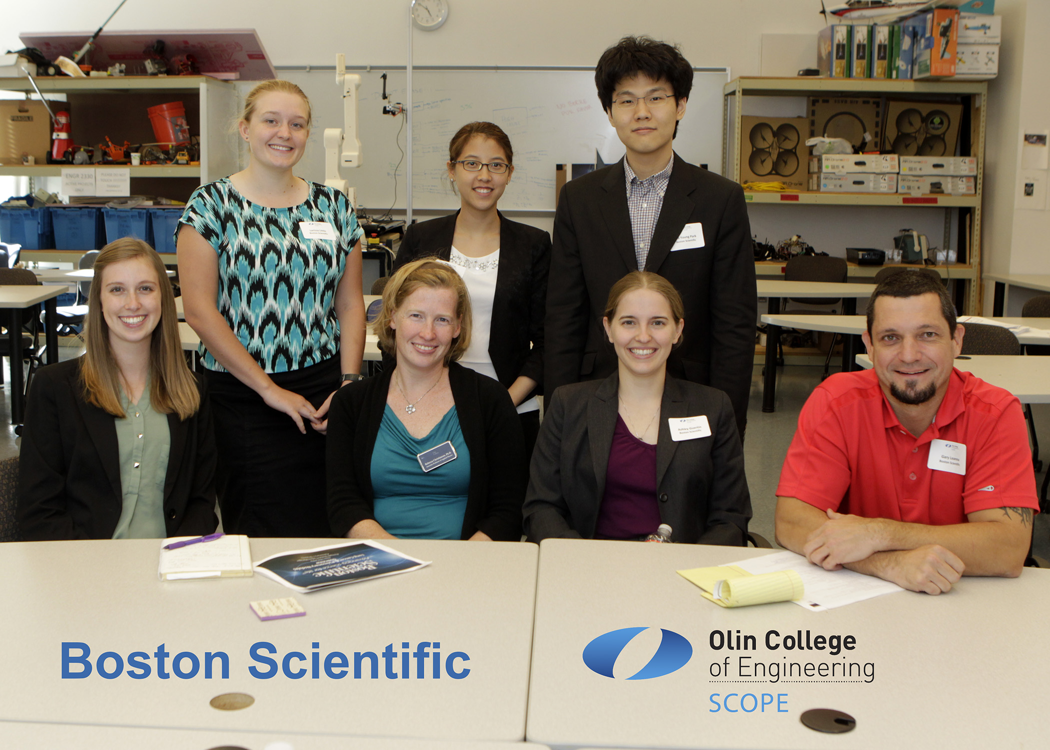 Team members sitting and standing around a desk smiling