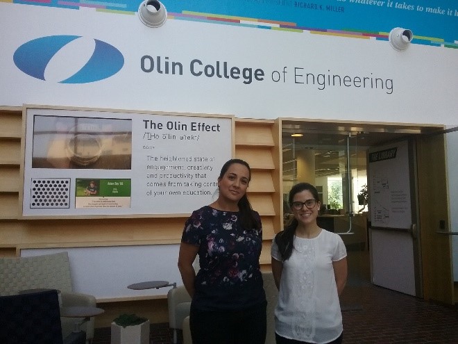 Two people standing in a building lobby beneath an Olin College of Engineering sign.