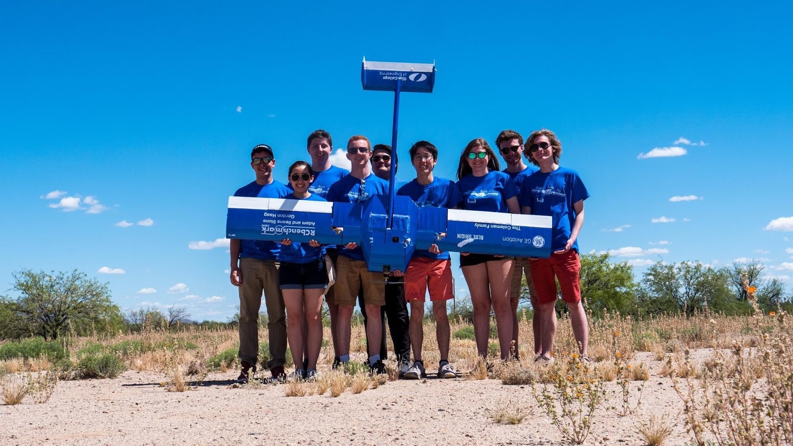 Group photo of Olin's Design Build Fly project team holding their airplane outside and wearing matching t-shirts.