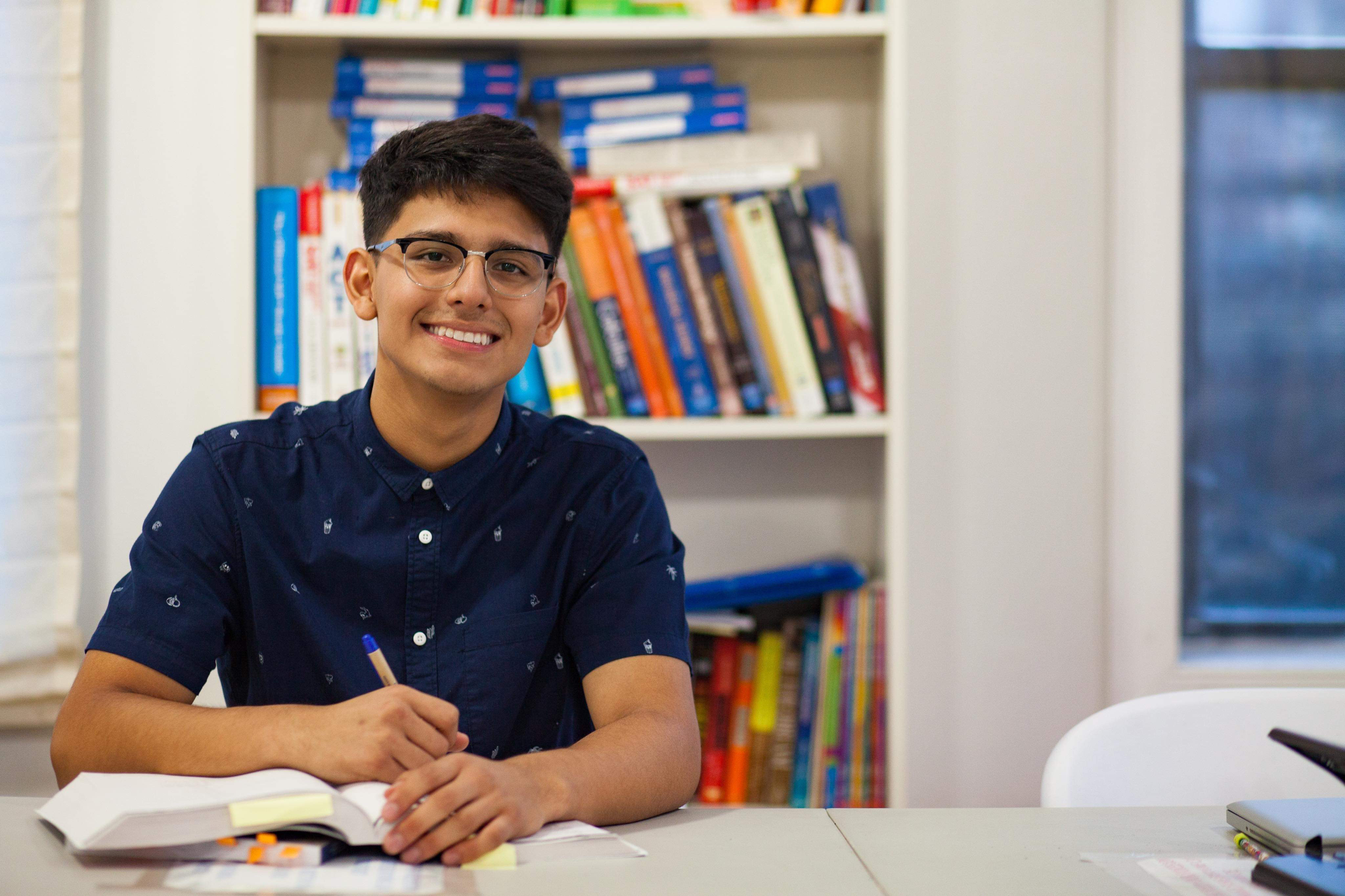 The author seated at a table with a pen and book.