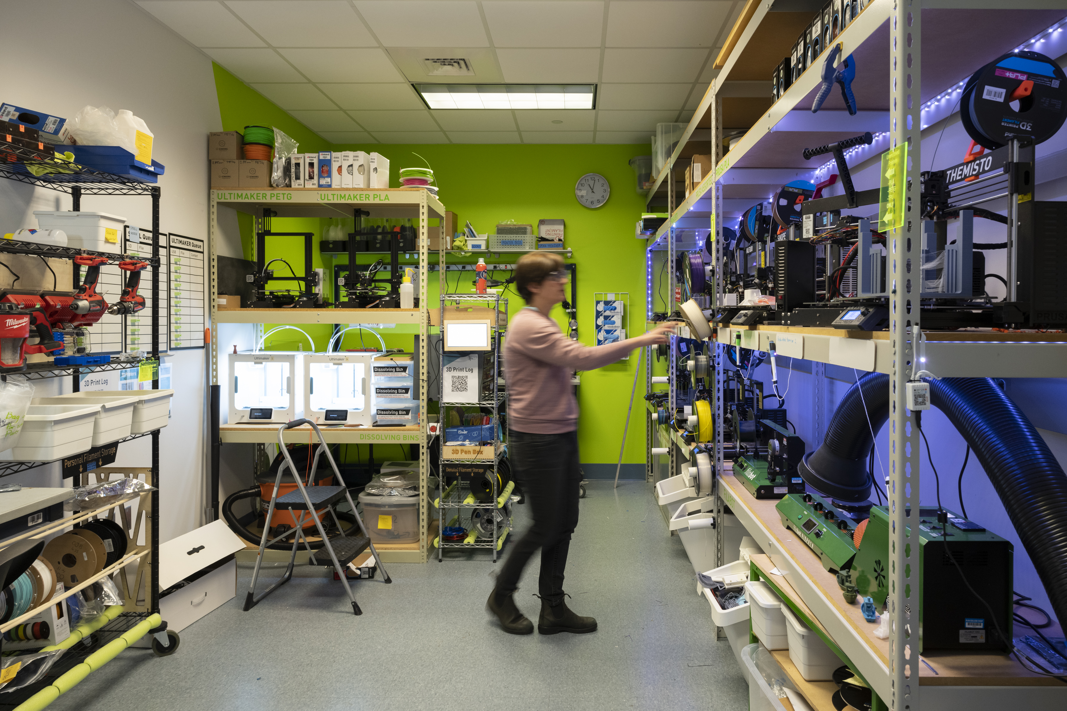 A faculty member can be seen walking in a classroom hub.