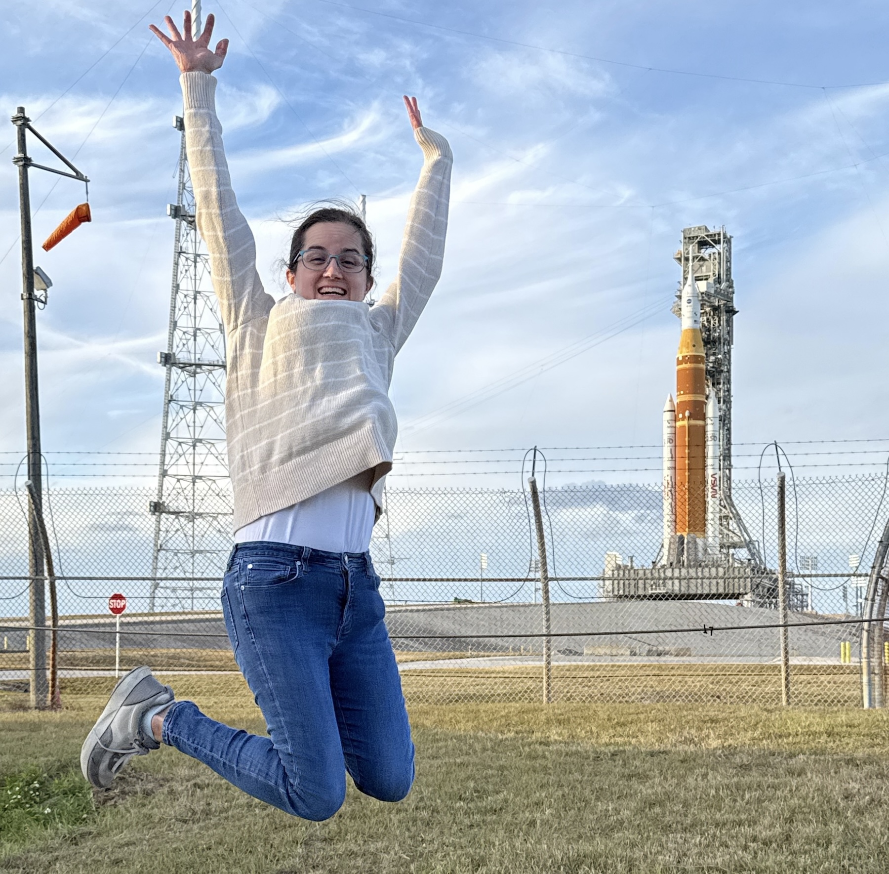 Ashley Walker '09 jumps into the air with a space craft in the background.