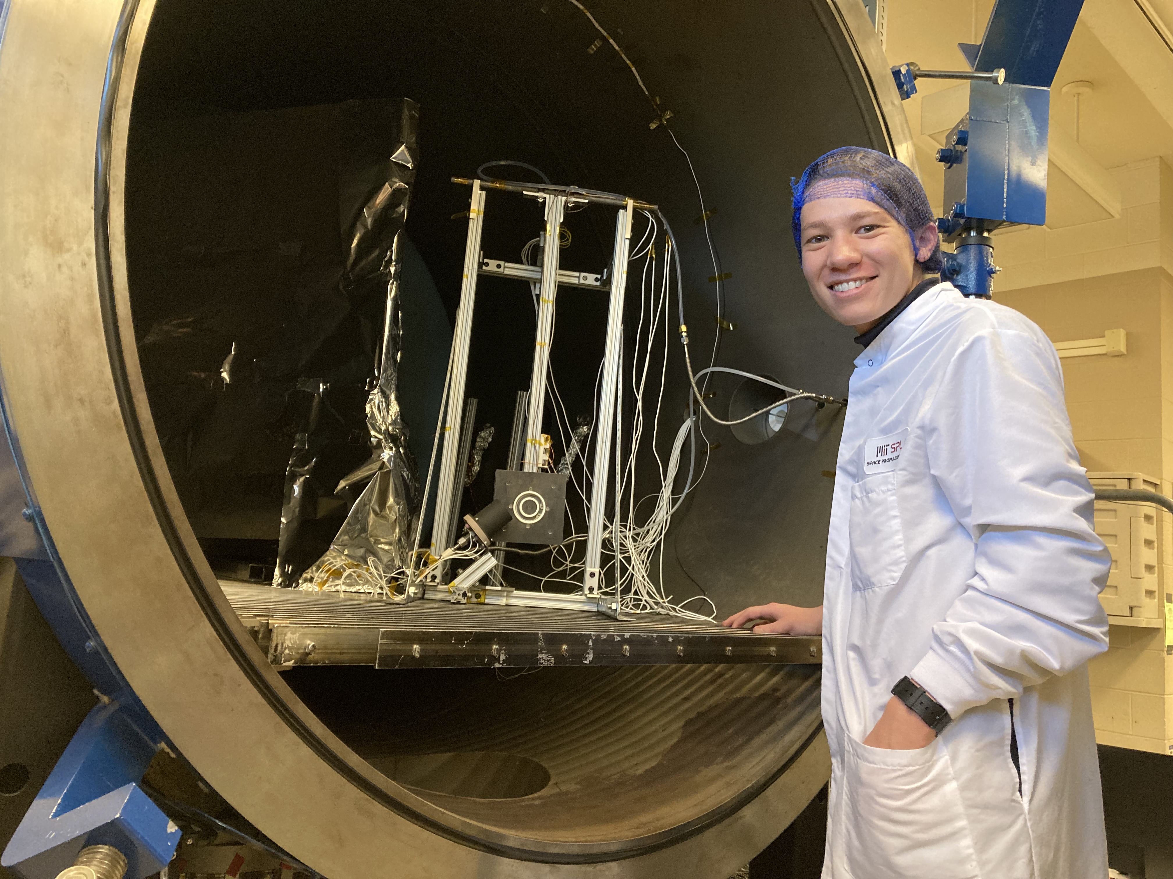 Braden Oh '23 poses with an ion thruster at MIT's Space Propulsion Lab in 2023.