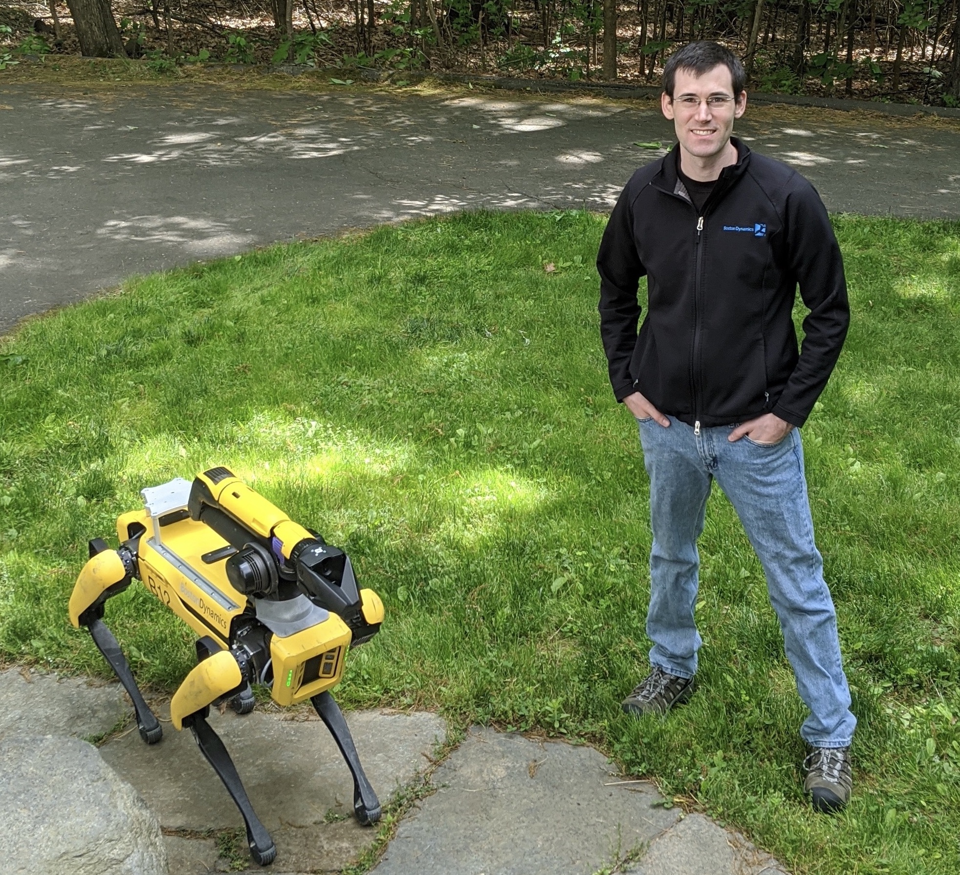 Andy Barry '10 stands next to Boston Dynamics' quadruped robot, Spot.