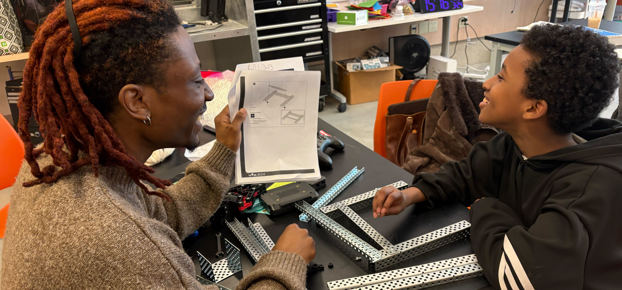 A student from the BOW Design Justice Studio (DJS) is pictured working with a young child in a classroom setting.