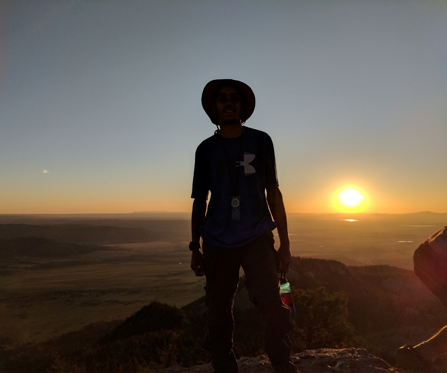 The author backpacking at a scenic overlook with a sunset in the background.