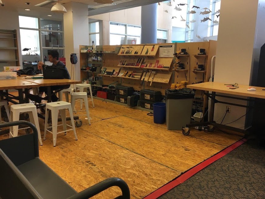 A table and stools next to shelves of tools.