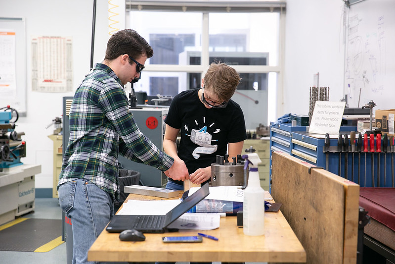 Two students wearing safety glasses and working together in the Olin Shop.