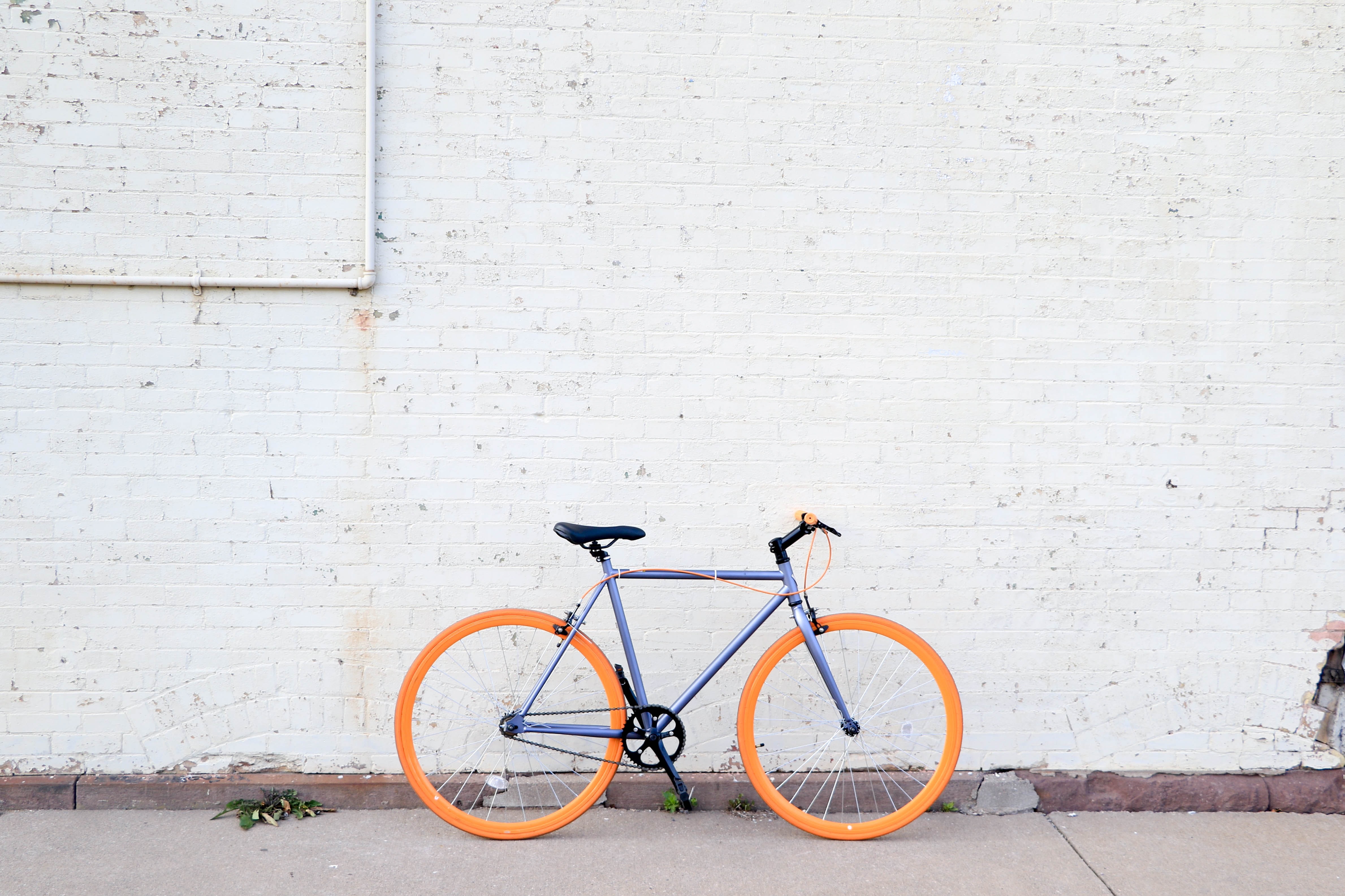 A bicycle on a sidewalk next to a white brick wall.