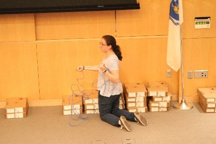 A student organizing boxes of laptops on the floor of Olin's Norden Auditorium.