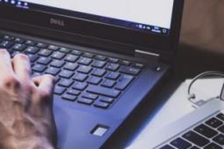 Closeup of a person working with two laptops.
