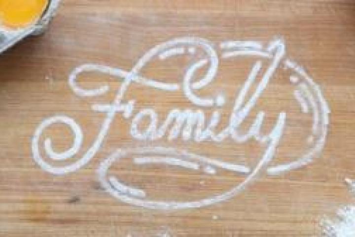 A wooden surface with baking supplies and "Family" written with flour.