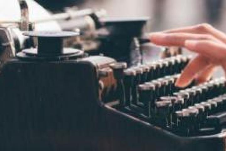 A closeup of a person typing on a typewriter.