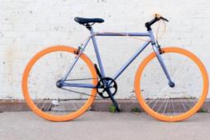 A bicycle on a sidewalk next to a white brick wall.