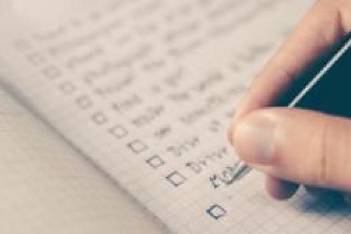Closeup of a person writing a checklist in a notebook.