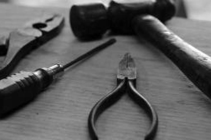 Black and white closeup of tools on a plank of wood.