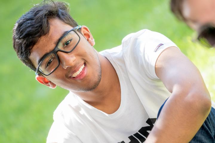 Olin College Admission Ambassador Sparsh Bansal A photo of a young man sitting in the grass and smiling
