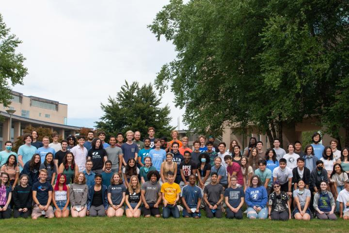A photo of a group of 86 students sitting outside on the lawn