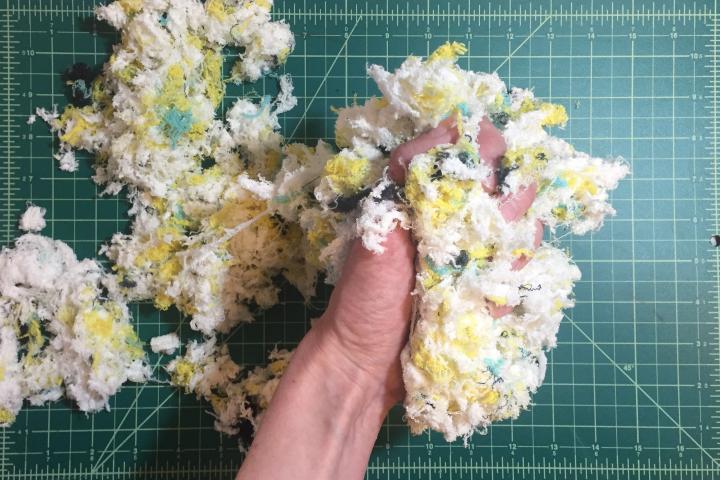 A photo of a hand holding the cut up stuffing of a quilt