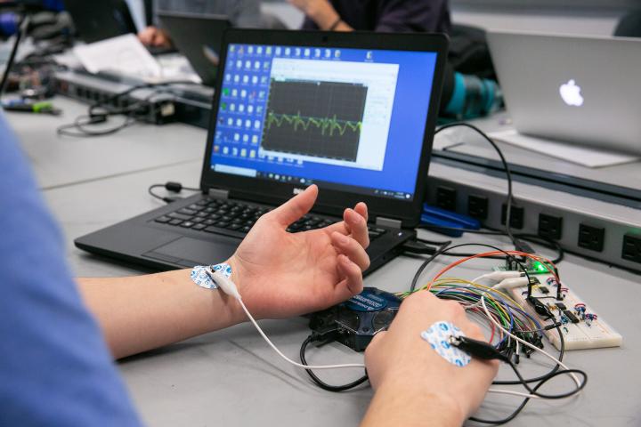 A photo of a laptop with wires connecting it to a person who is wearing electrodes