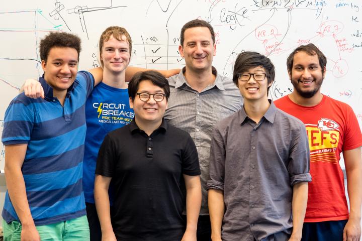 A photo of a group of six people standing close to one another smiling