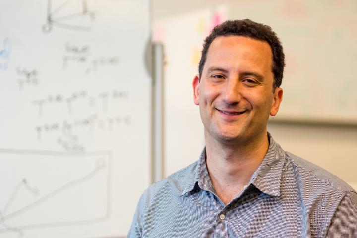Paul Ruvolo, Associate Professor of Computer Science, in blueish grey shirt, smiles for a photo.