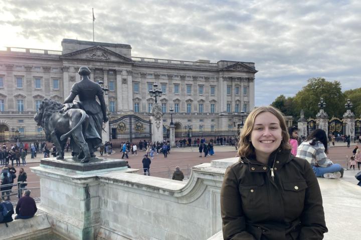 A photo of a person standing in front of Buckingham Palace in London England
