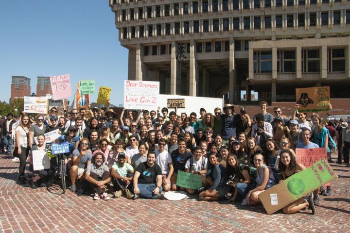 A large group of people gather and hold signs at a climate protest in Boston, MA. 