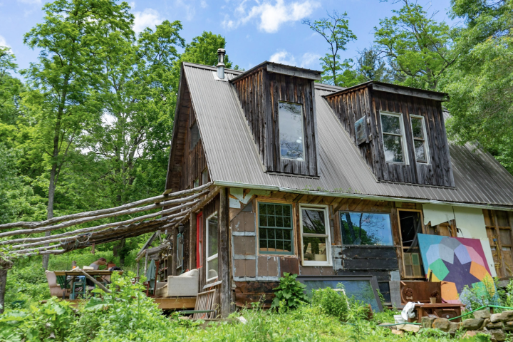 A brown house surrounded by green foliage as part of the larger Woodland Farms