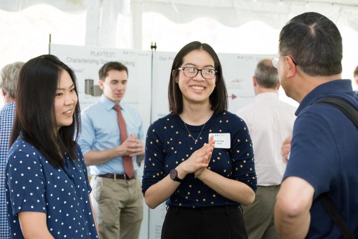 Three people talk under a large white tent during an Olin event