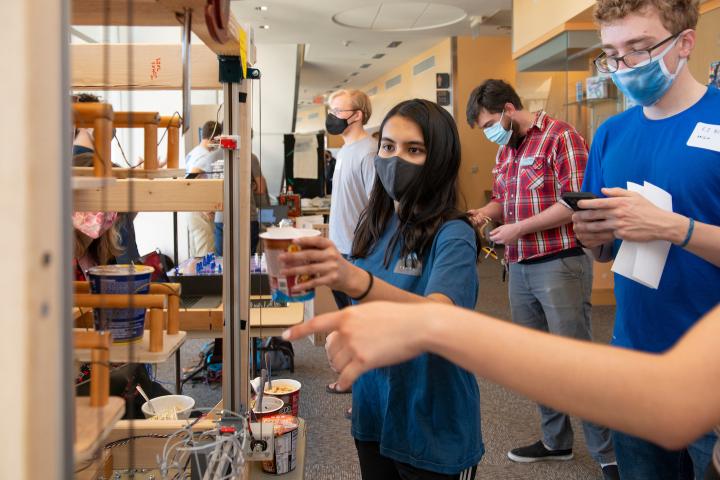 A student waits for a Cup 'O Noodles to be made from a student-designed machine at Expo 2021.