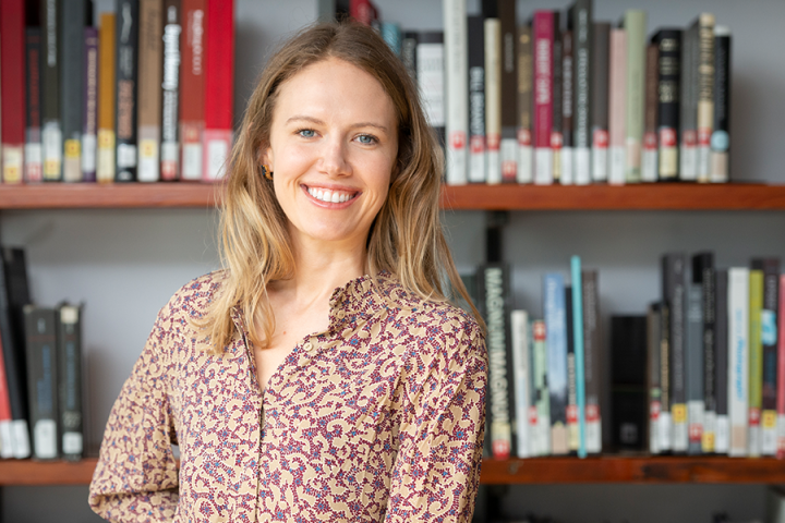 A photo of Whitney Lohmeyer standing in front of a shelf full of books