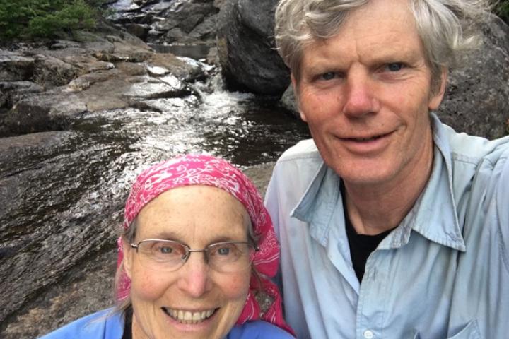 A photo of a couple standing in front of a stream
