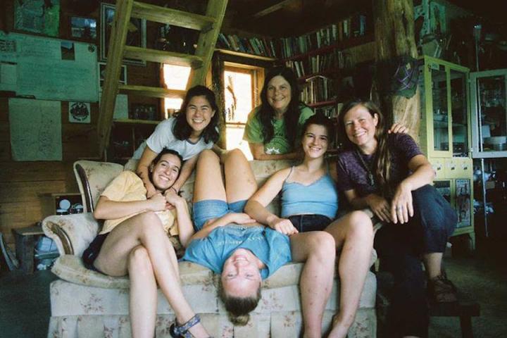 Olivia Seitelman ’22, Sophia Borovikova ’24, Stella Stark ’24 and Caitlin Kantor ’23 pose with the family owners of the Farm. Six people pose in various positions on and behind a couch.