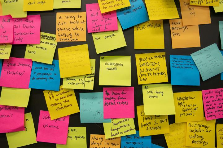 An arrangement of multi-colored sticky notes adorn a classroom wall. An arrangement of multi-colored sticky notes adorn a classroom wall.