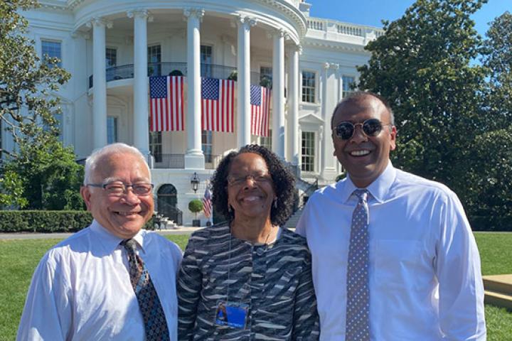 A photo of three people standing in front of the White House