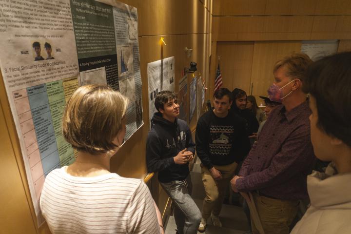Students and faculty are shown in a semi-circle, based around a poster project on a wall in the Nord.. Students and faculty are shown in a semi-circle, based around a poster project on a wall.