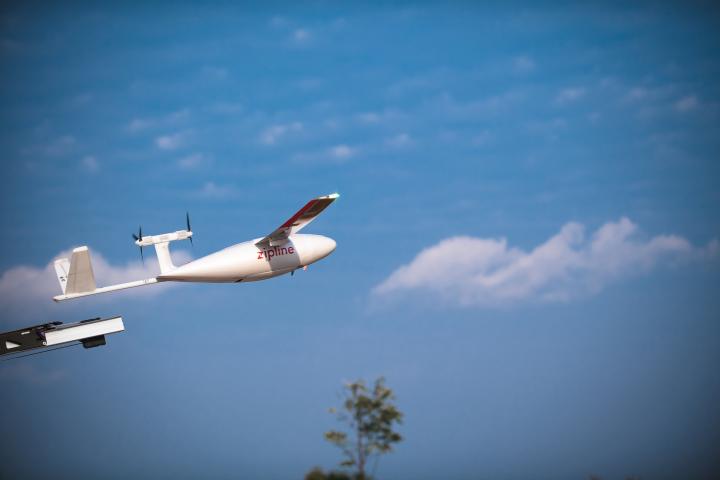 A Zipline plane/auto-delivery system flying across the sky.